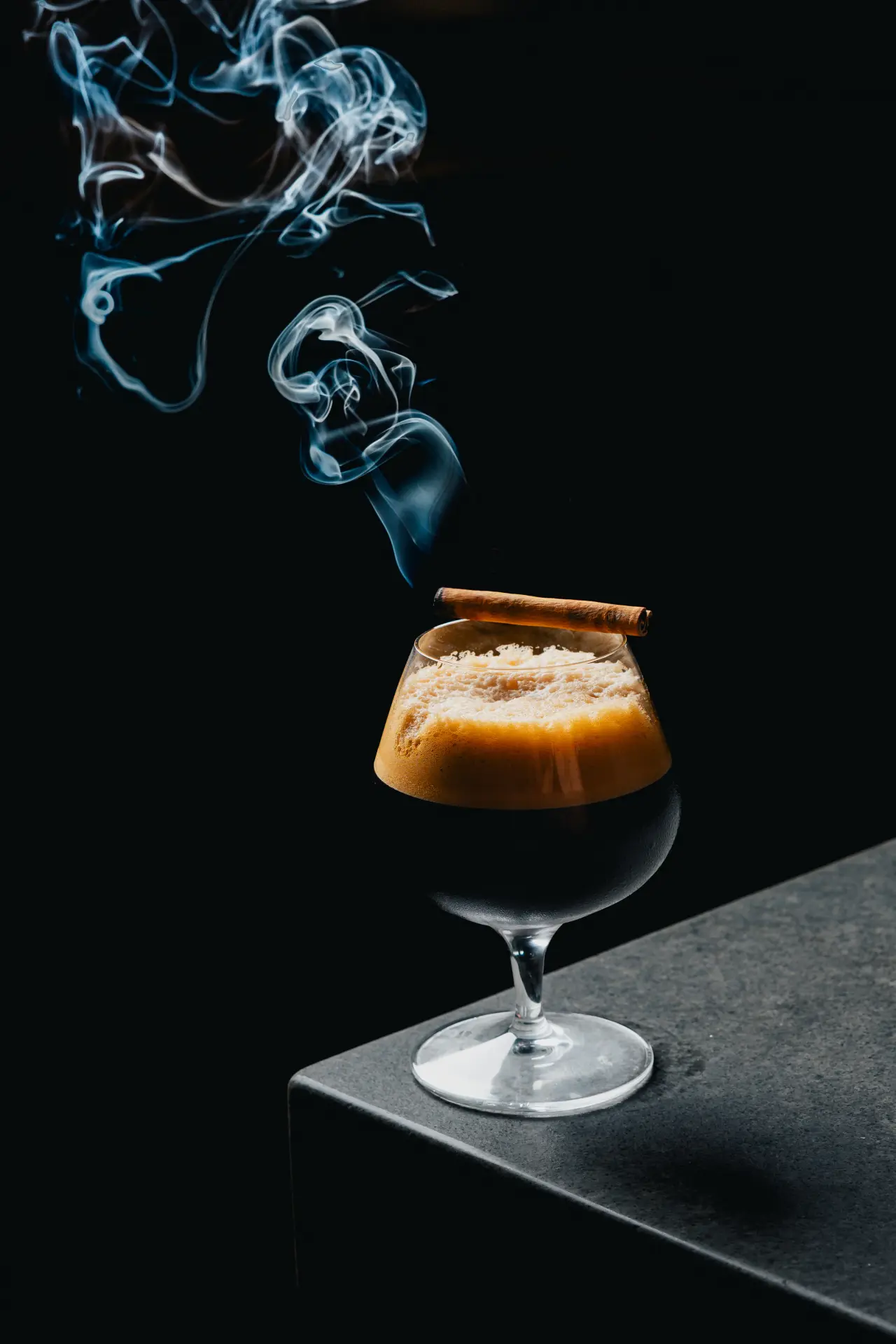 A smoked cocktail in a snifter with a cinnamon garnish